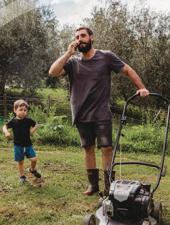 Father and young son stand in backyard ready to mow the lawns