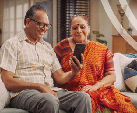 Couple sitting on couch both look into phone screen.