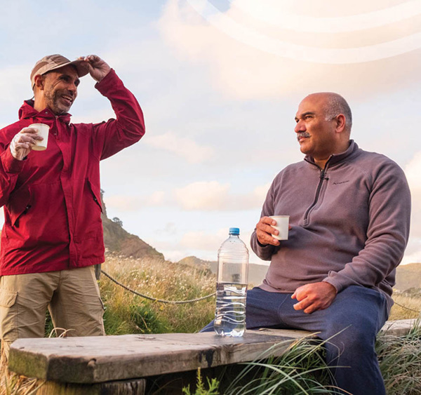 Two people sitting outdoors, one gesturing while speaking