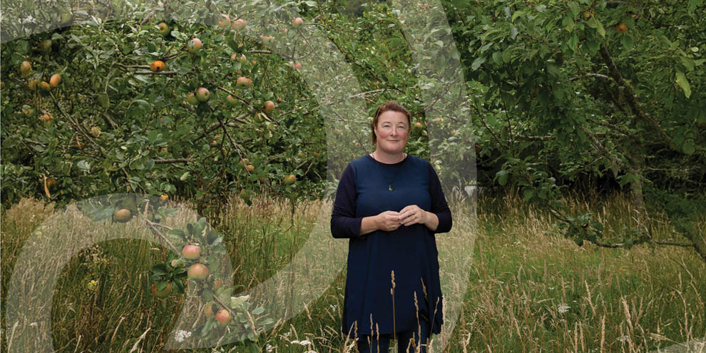 Jodi standing is a garden of fruit trees and long grass