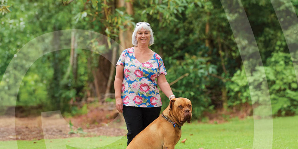 Lisa stands next to her dog outdoors.